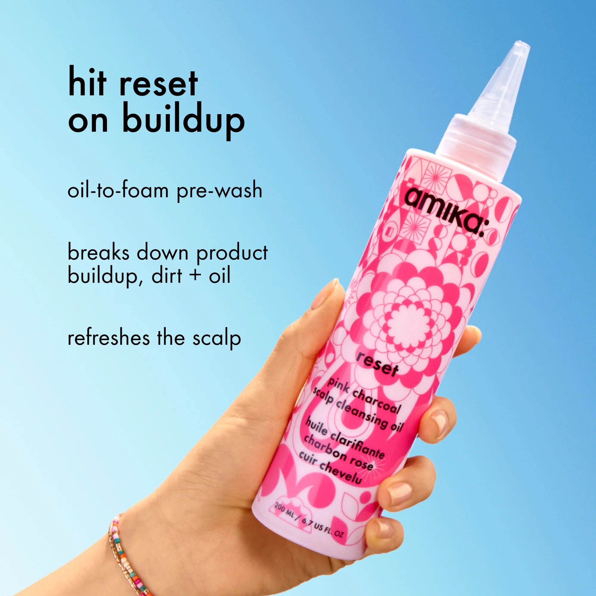 Pink charcoal scalp cleansing oil bottle with pump nozzle in hand