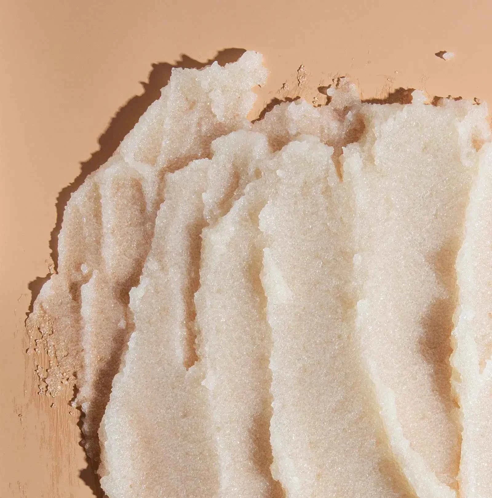 Exfoliating scrub granules in a white, grainy paste