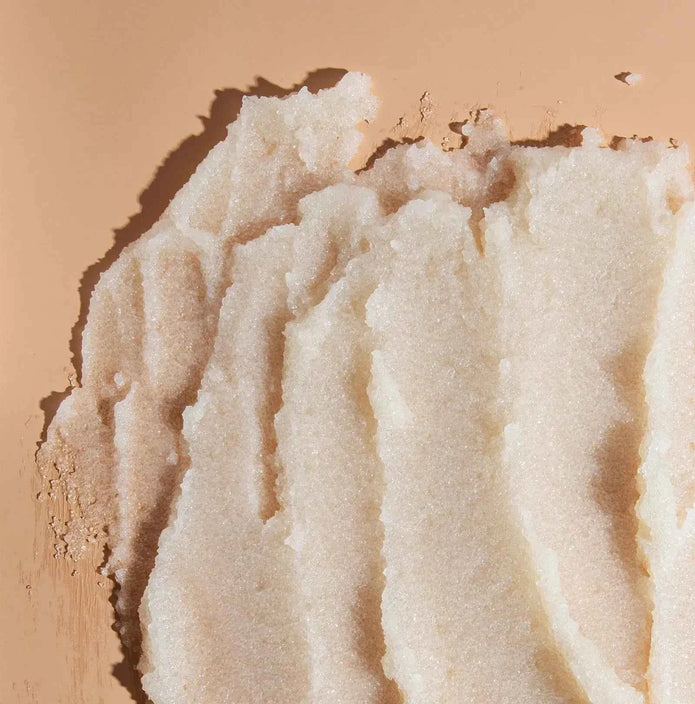 Exfoliating scrub granules in a white, grainy paste