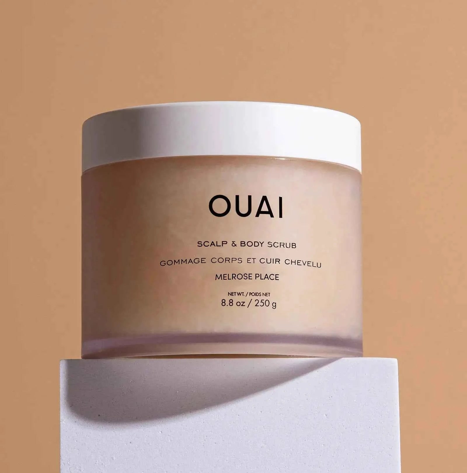Ouai scalp and body scrub jar with white label on cream container