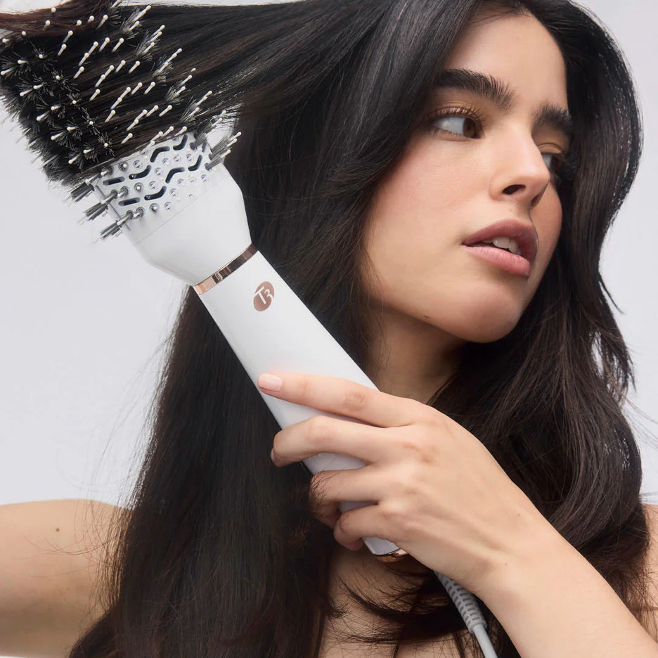 White heated brush styling dark hair with black bristles and rounded barrel head