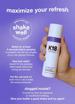 K18 AirWash dry shampoo bottle held upright by hand with purple cap