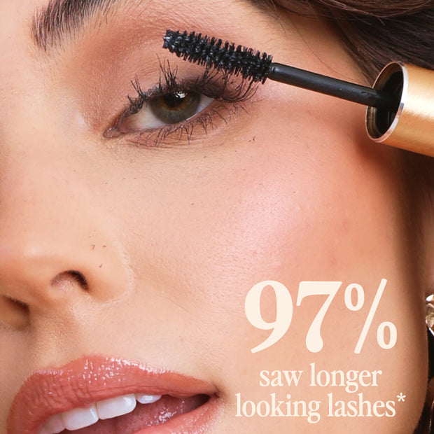 Black mascara brush applicator applying on eye lashes, close-up for fuller look
