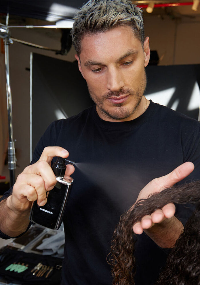 Stylist applying Extra Strength Dream Coat anti-frizz spray with black trigger bottle