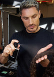 Stylist applying Extra Strength Dream Coat anti-frizz spray with black trigger bottle