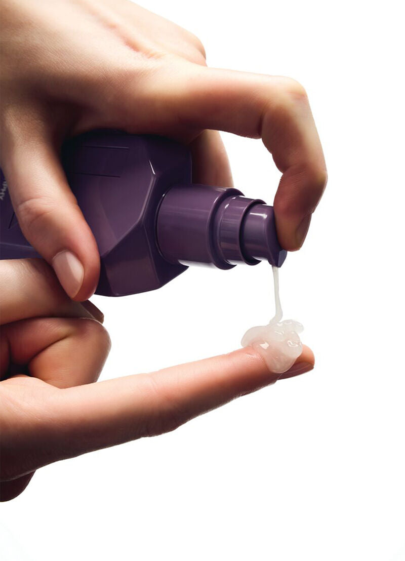 Hands dispensing clear gel from Night.Shift bottle, purple cap