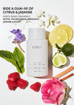 Hair gloss bottle with lemon, flowers, and fruit on display
