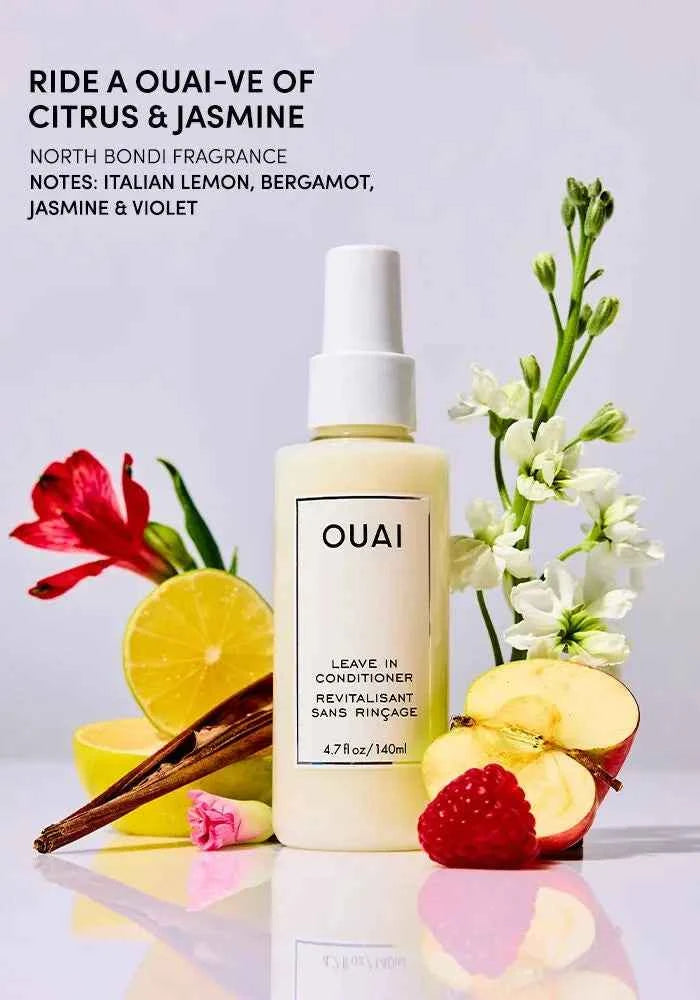 OUAI leave-in conditioner bottle with white pump surrounded by flowers and fruit