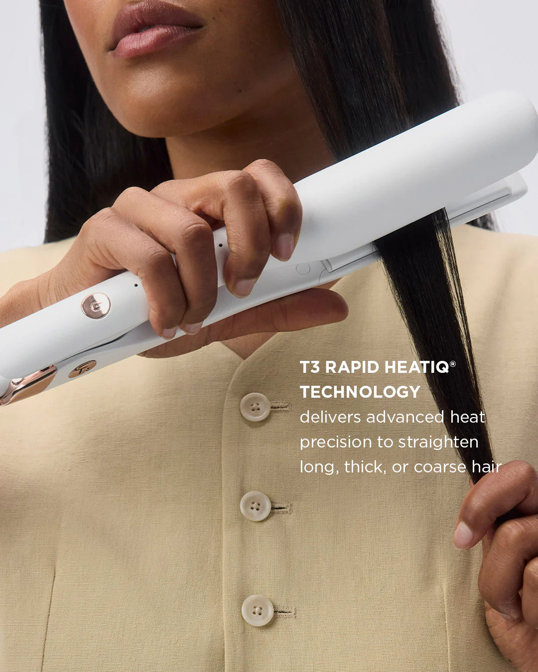 Hands holding a white flat iron to straighten dark hair near the ends