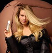 OUAI Thickening Spray bottle held in hand with white pump top