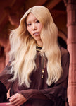 Model with long blonde hair styled with volume and waves, side profile indoors