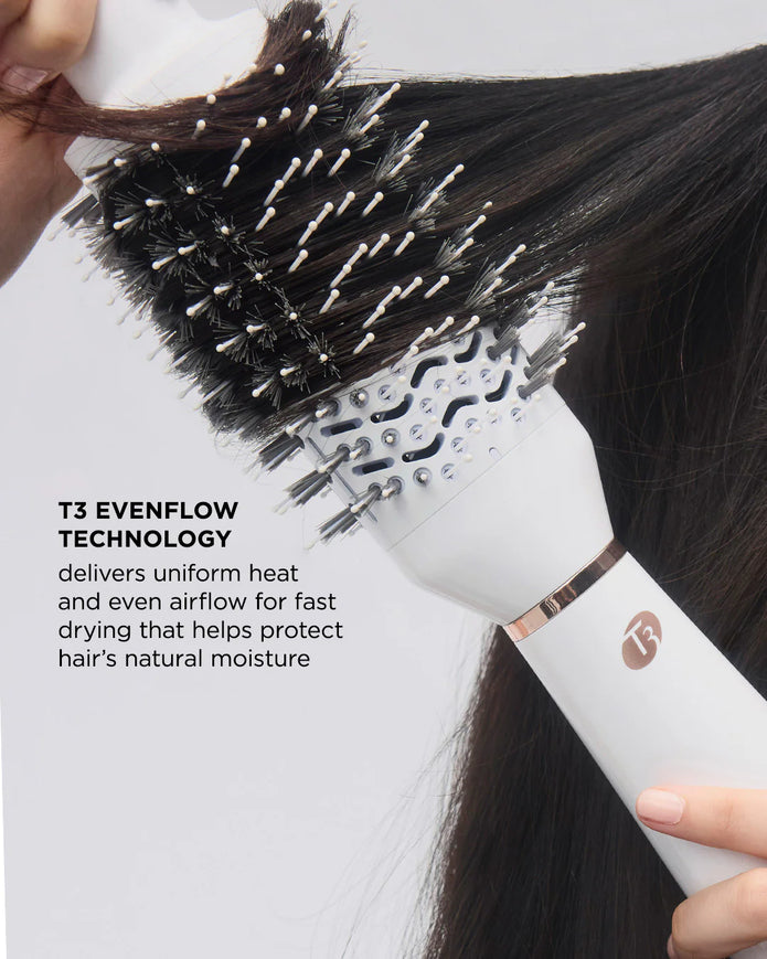 White heated hair styling brush held in hand, showing black bristles on head