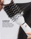 White heated hair styling brush held in hand, showing black bristles on head