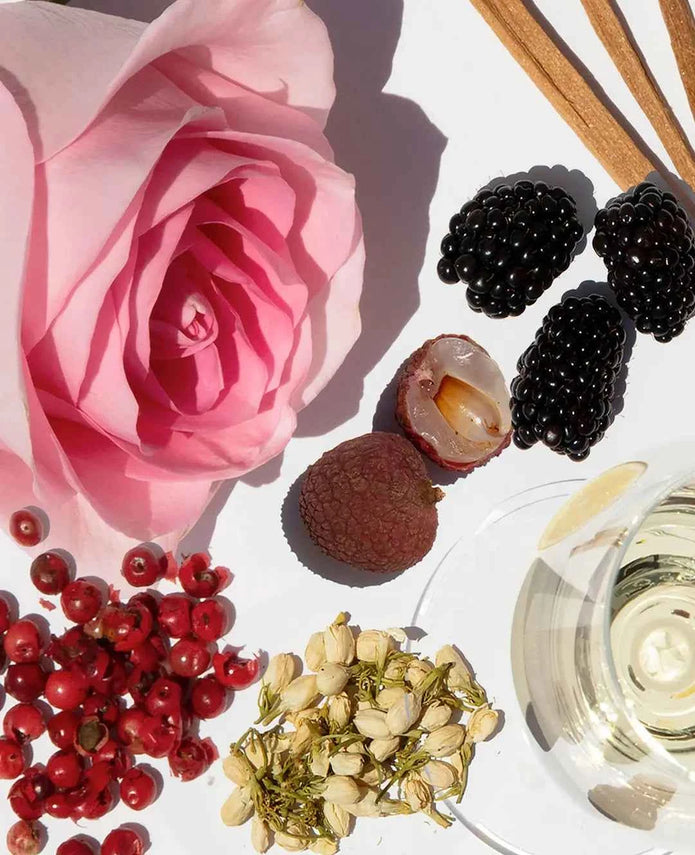 Body scrub cream in a dish with exfoliating granules, rose and berries nearby