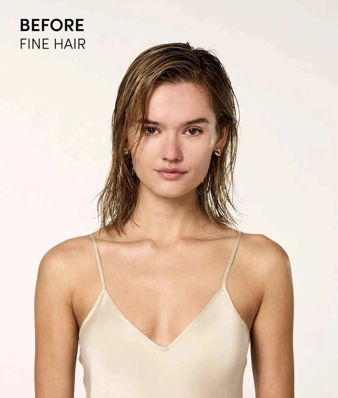 Woman holding OUAI leave-in conditioner bottle with white pump, with wet hair